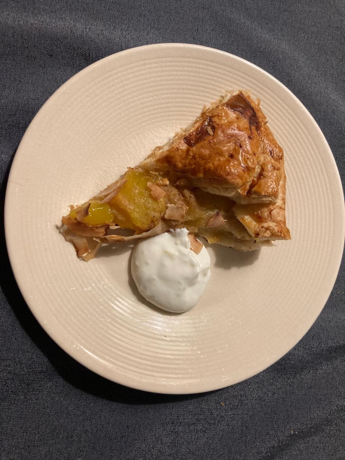 Slice of pie with a dollop of cream on a beige plate.
